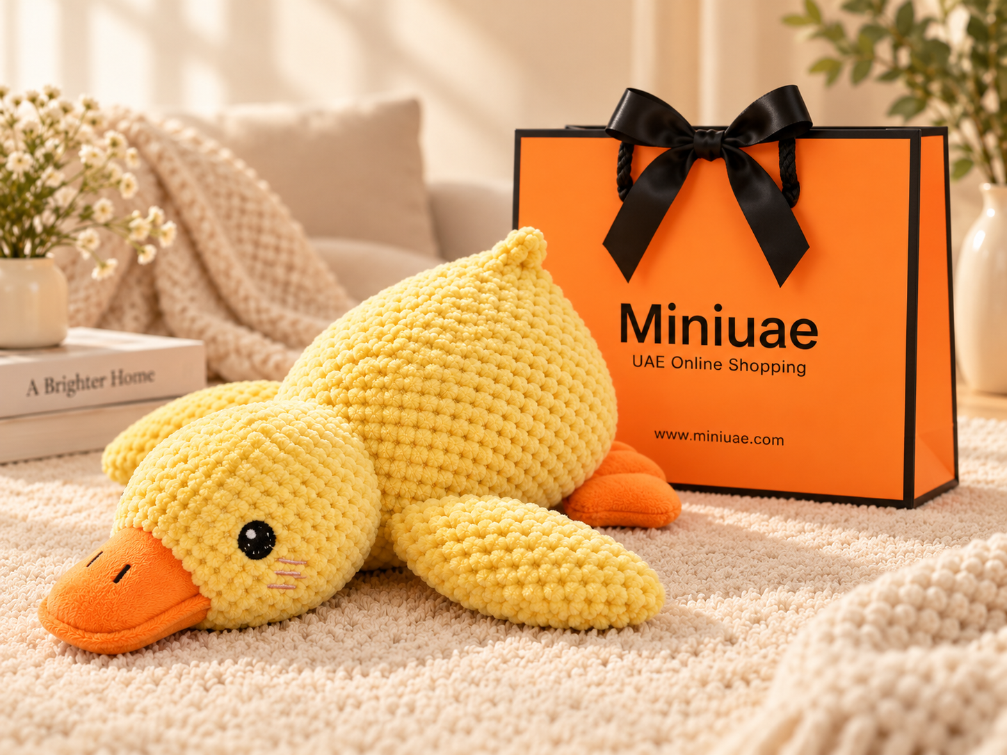 Yellow plush duck beside the orange Miniuae gift bag and black ribbon